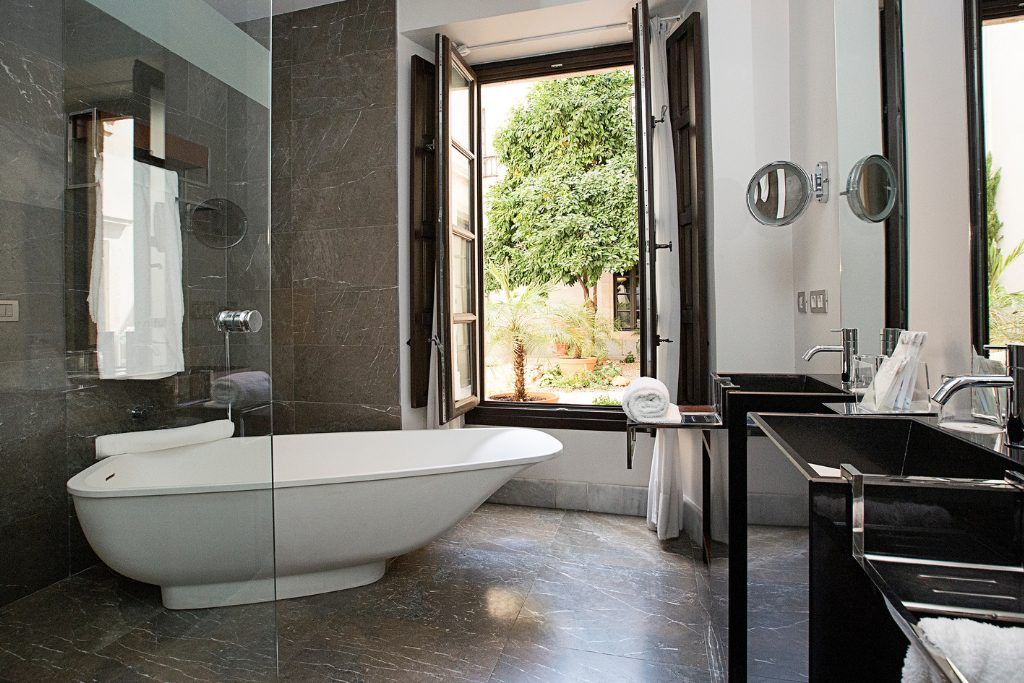 The bathroom with a modern tub and an open window at Hospes Palacio del Bailio.