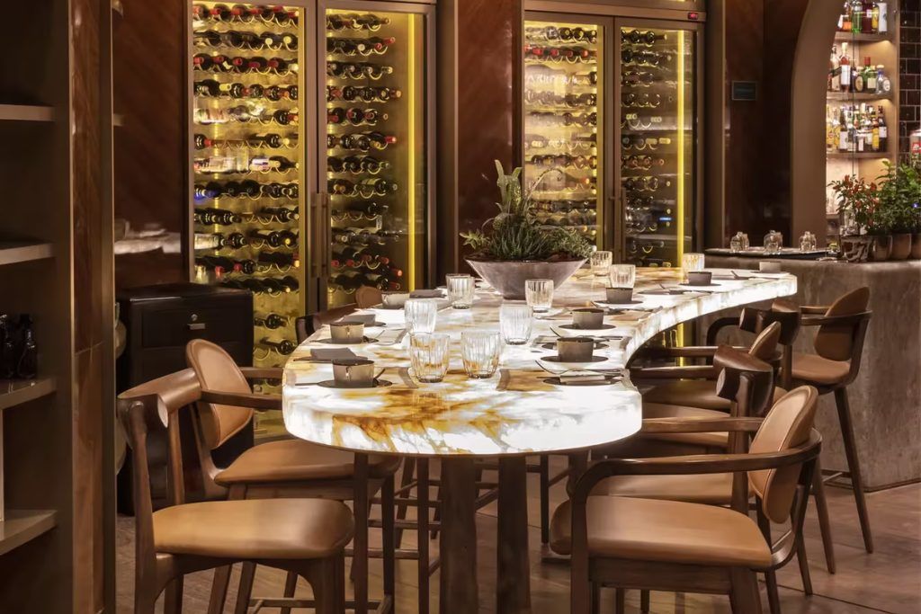 A long table in the Rosewood Sao Paulo's restaurant with a wine cellar in the background.