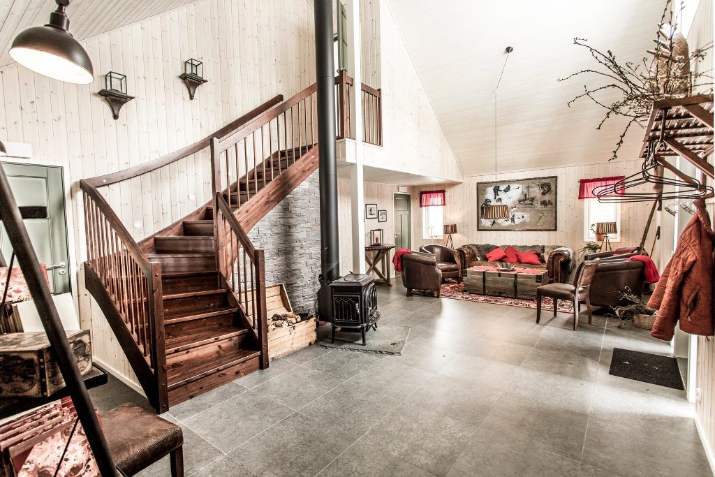The living room with a wood burning stove and a large staircase at Fjellborg Arctic Lodge.