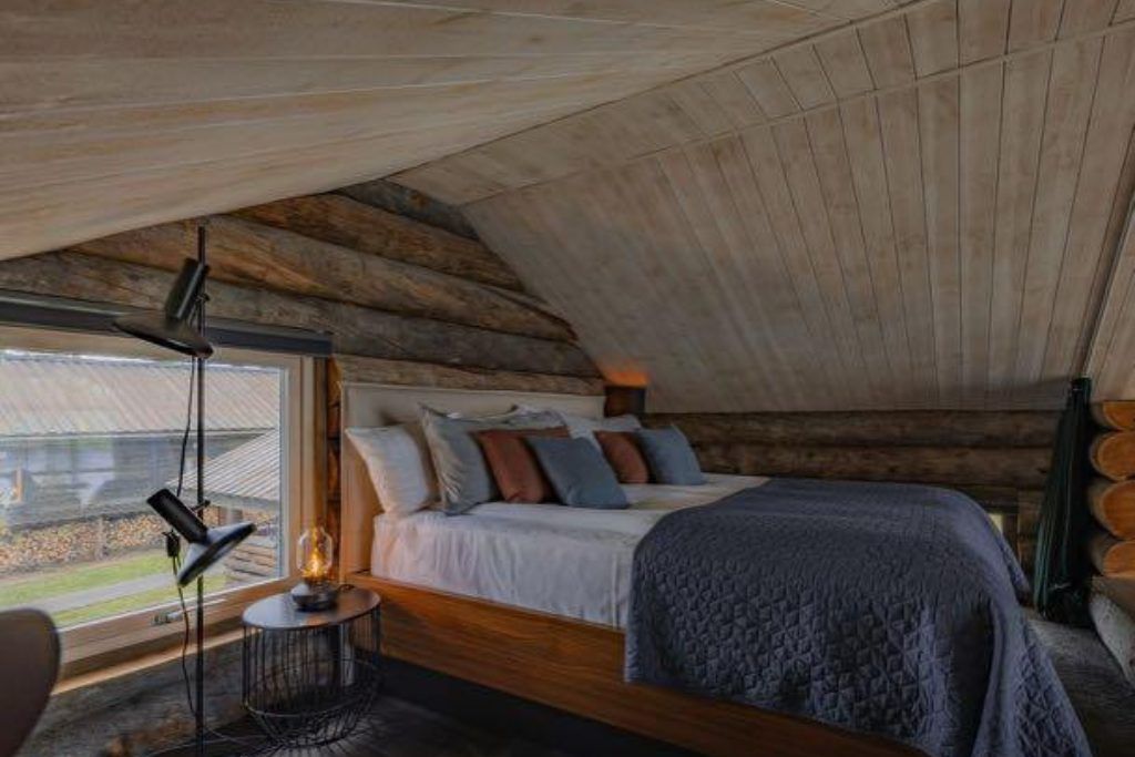 A bedroom with wooden accent and log walls at Arctic Retreat in Swedish Lapland.