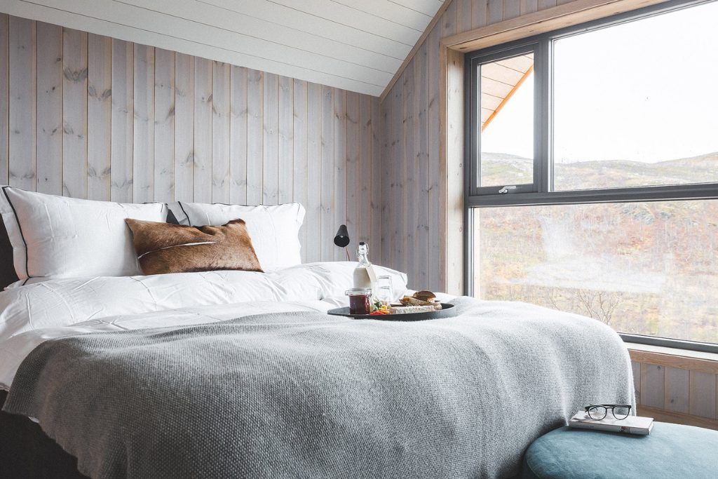 One of the sunny bedrooms at Skaret Lodge with a bottle and snacks on the bed.