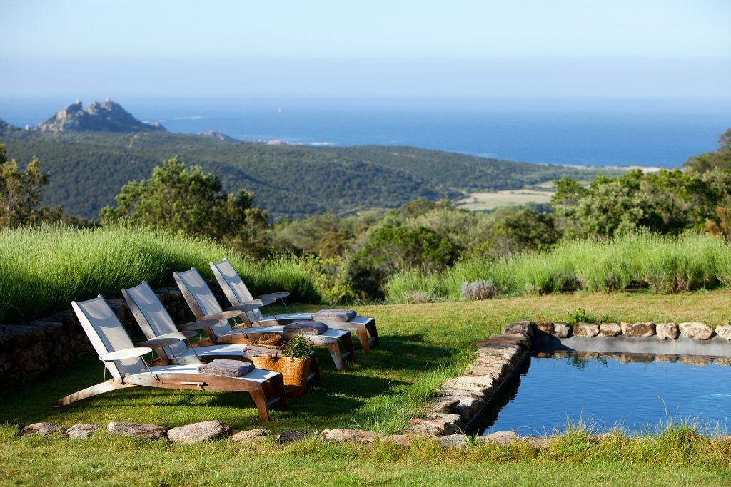 An outdoor swimming pool with loungers at Domaine de Murtoli.