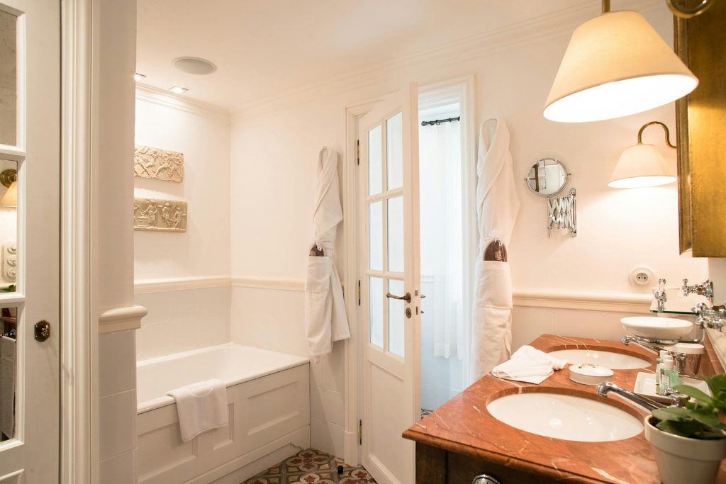 A white bathroom with a tub in one of the rooms at La Bastide.