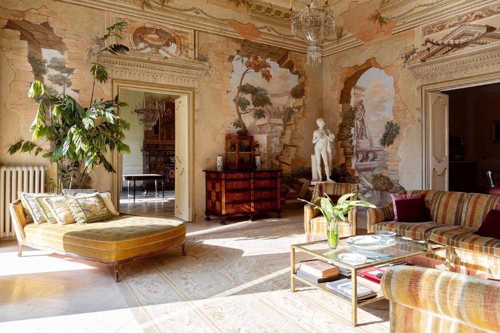 The decorated lobby of the Villa Tasca with statues in the corner and paintings on the walls.