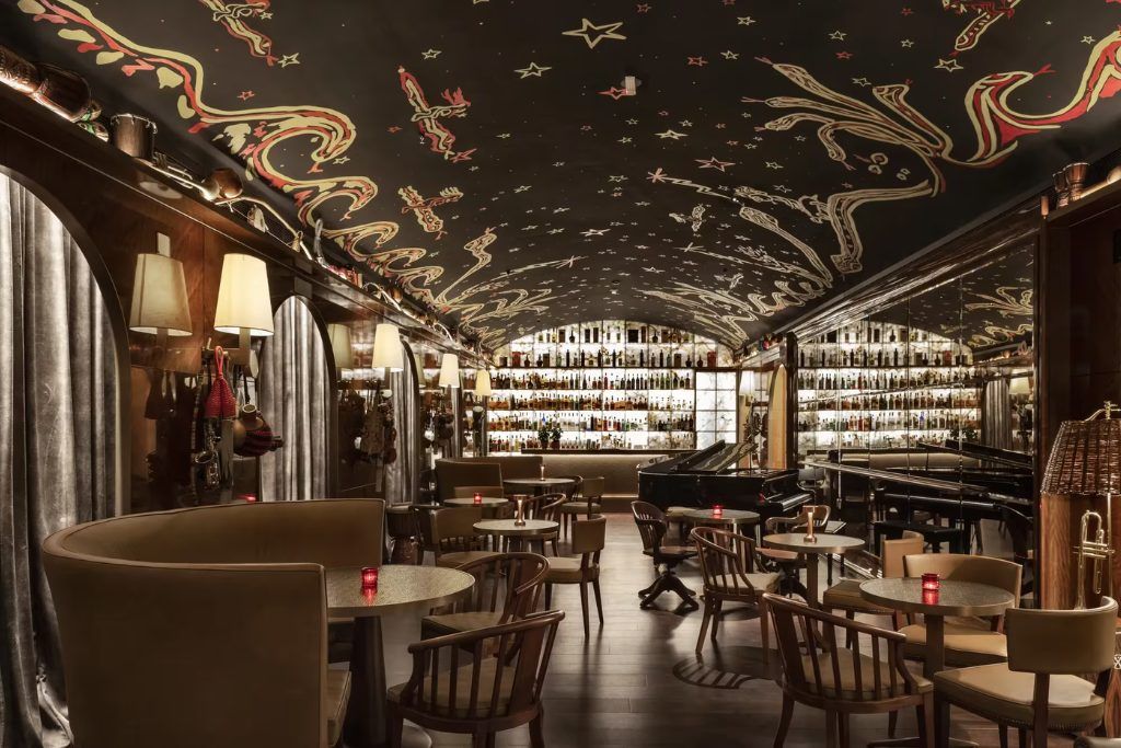 Several tables in a dimly lit restaurant at the Rosewood Sao Paulo with a bar in the background.