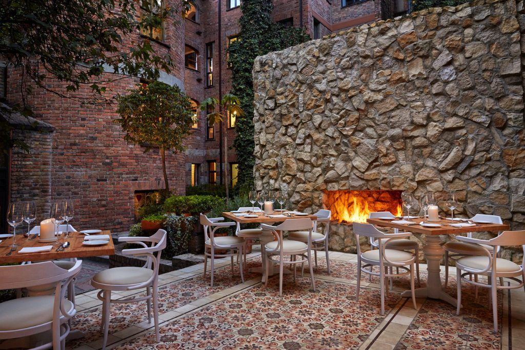 The patio at the Four Seasons Casa Medina in Bogota with a fireplace and tables and chairs.
