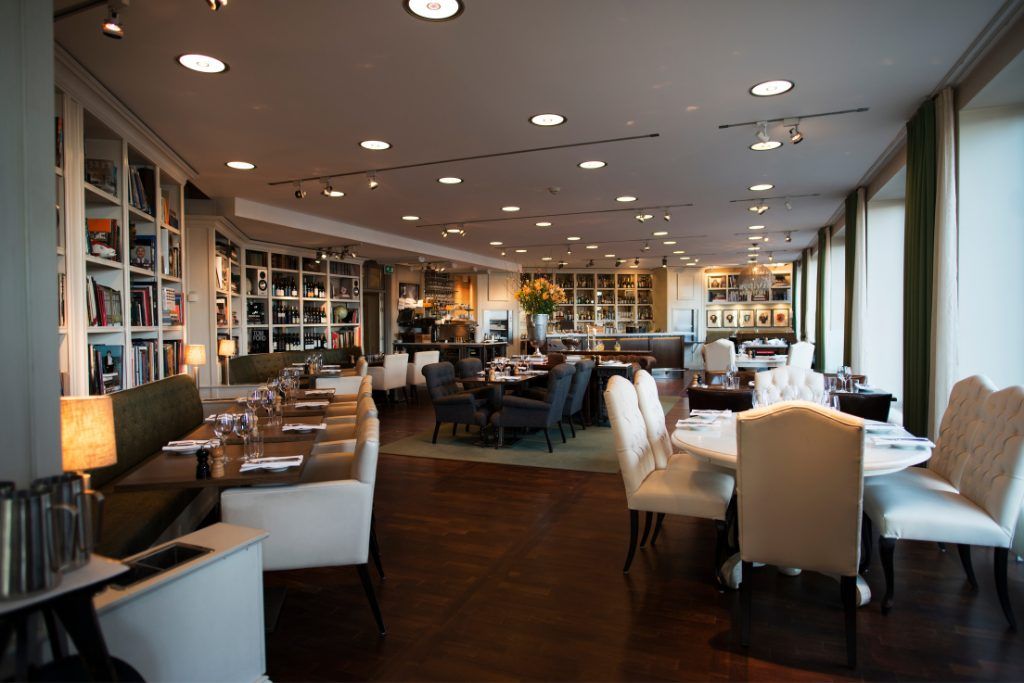 A dining area with multiple chairs, tables, and couches in the Lydmar Hotel.