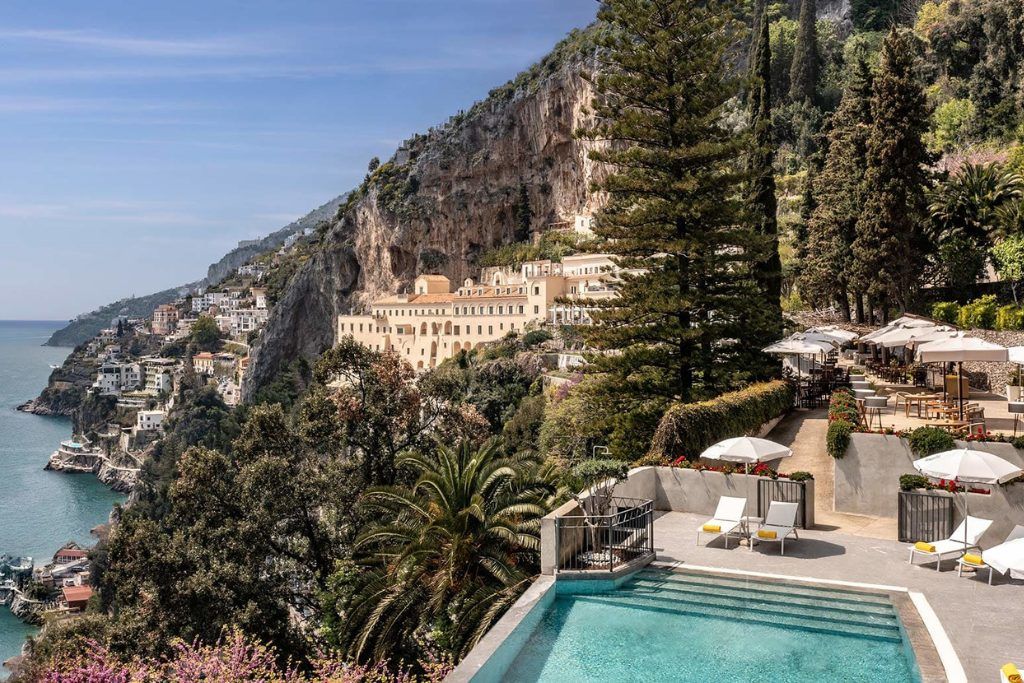 A daytime view of the Anantara Convento di Amalfi Grand Hotel and its swimming pool along the coast.