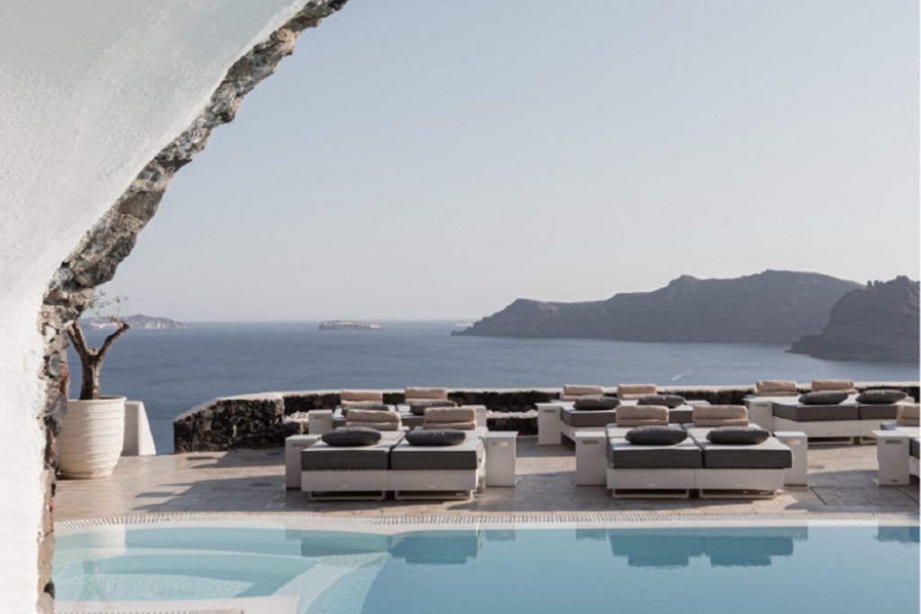 The outdoor swimming pool and loungers overlooking the water at Canavas Oia Suites.