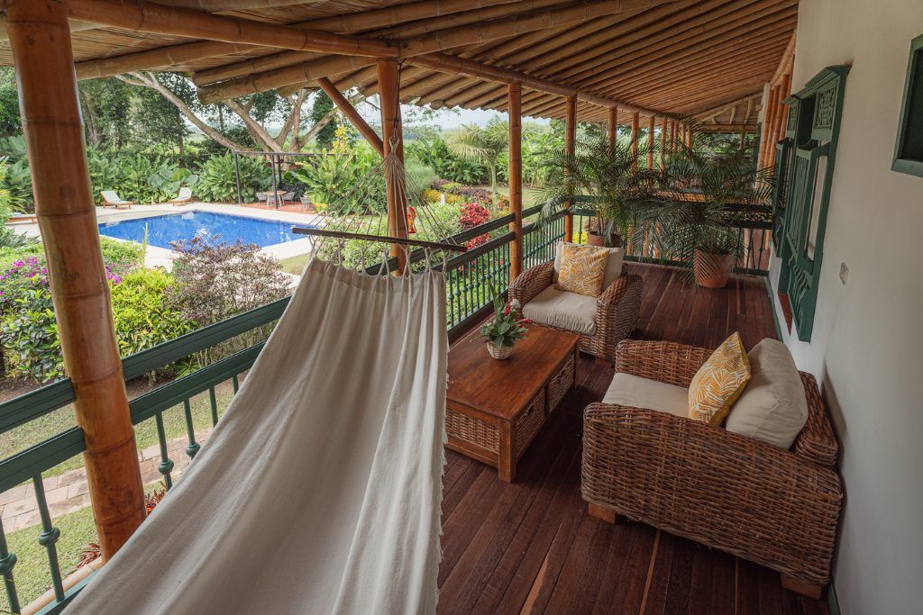 A hammock and two loungers on a covered porch at Hacienda Bambusa.