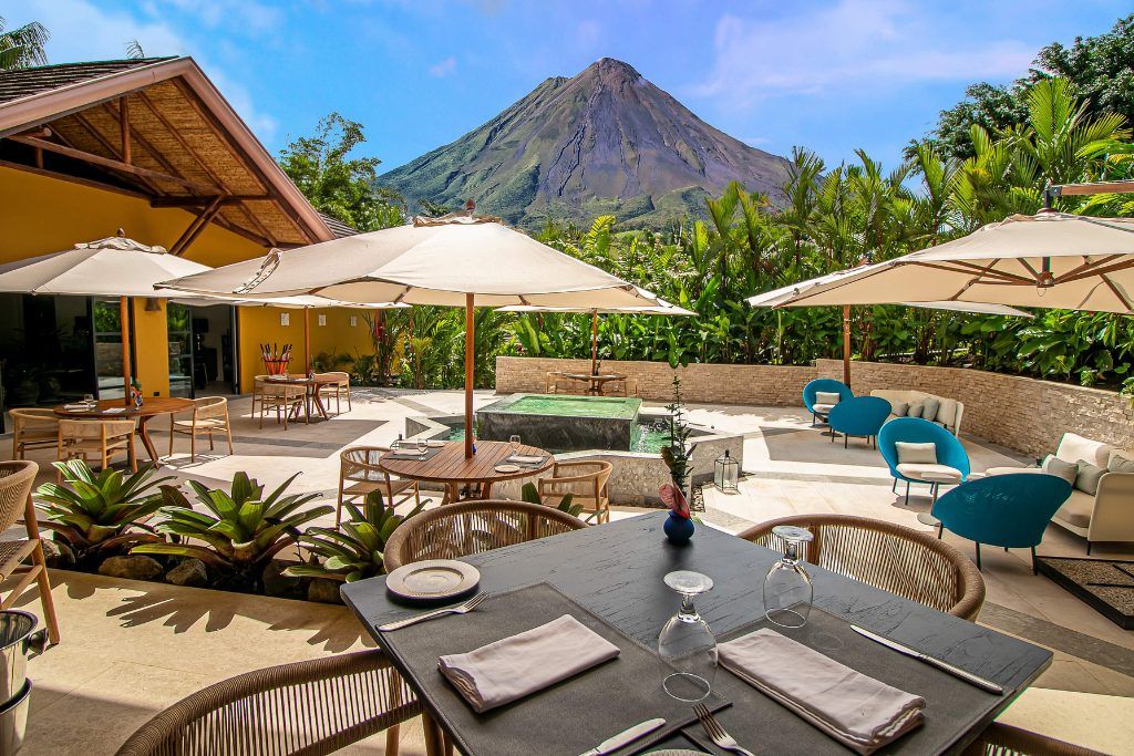 An outdoor dining area with Arenal Volcano in the background.
