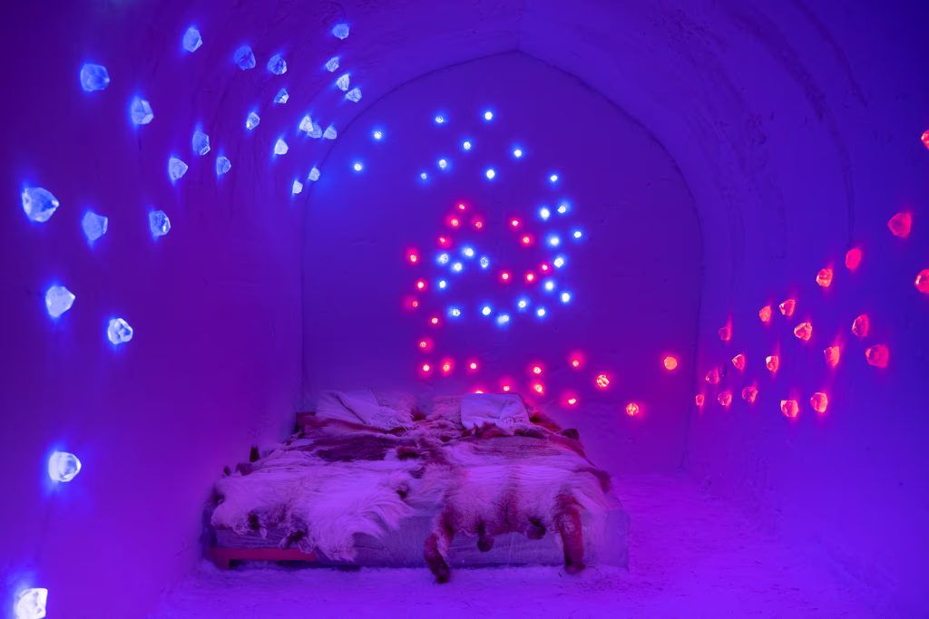 A dim room with colorful lighting and an ice bed in the Igloo Hotel at Sorrisniva Lodge.