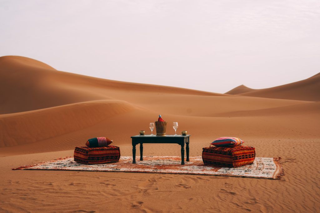 An outdoor lounge with a table with wine glasses in Private Desert Camp.