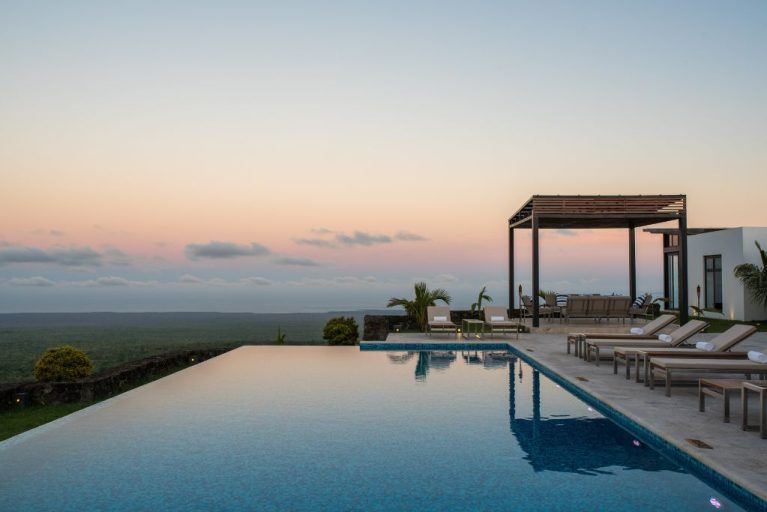 View of the sunrise behind a swimming pool at Pikaia Lodge in the Galapagos Islands