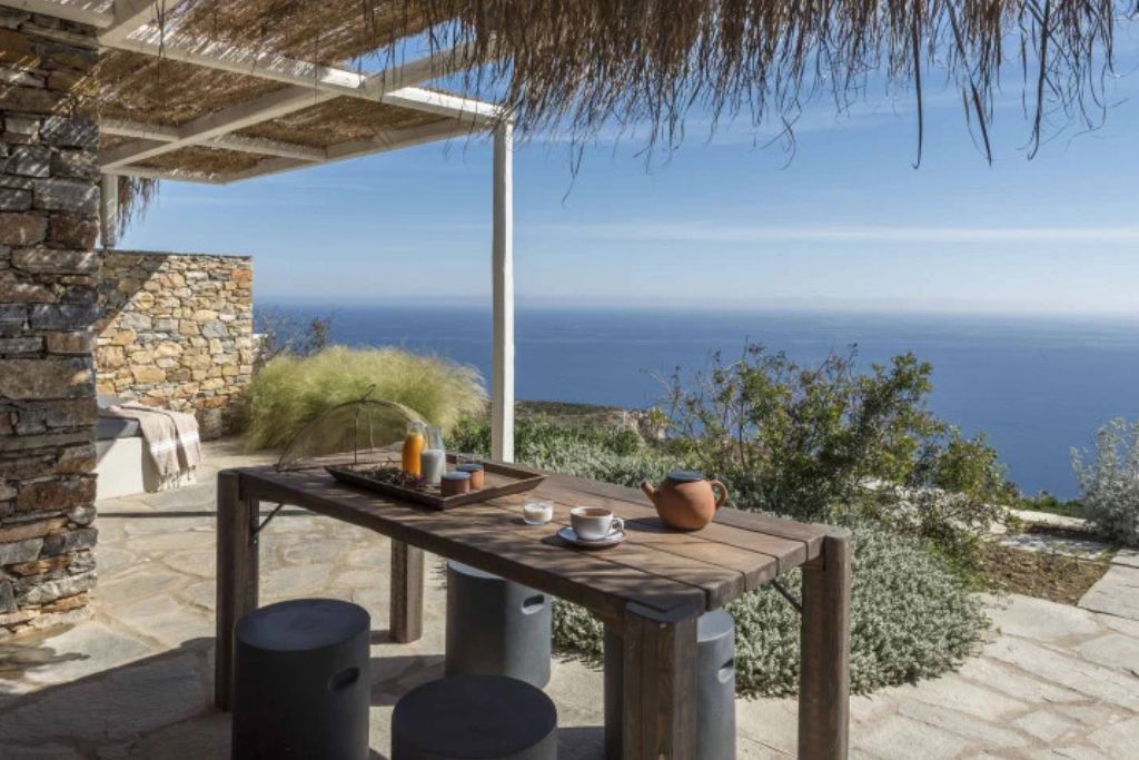 A dining table on a covered patio overlooking the ocean at the Verina Astra luxury hotel