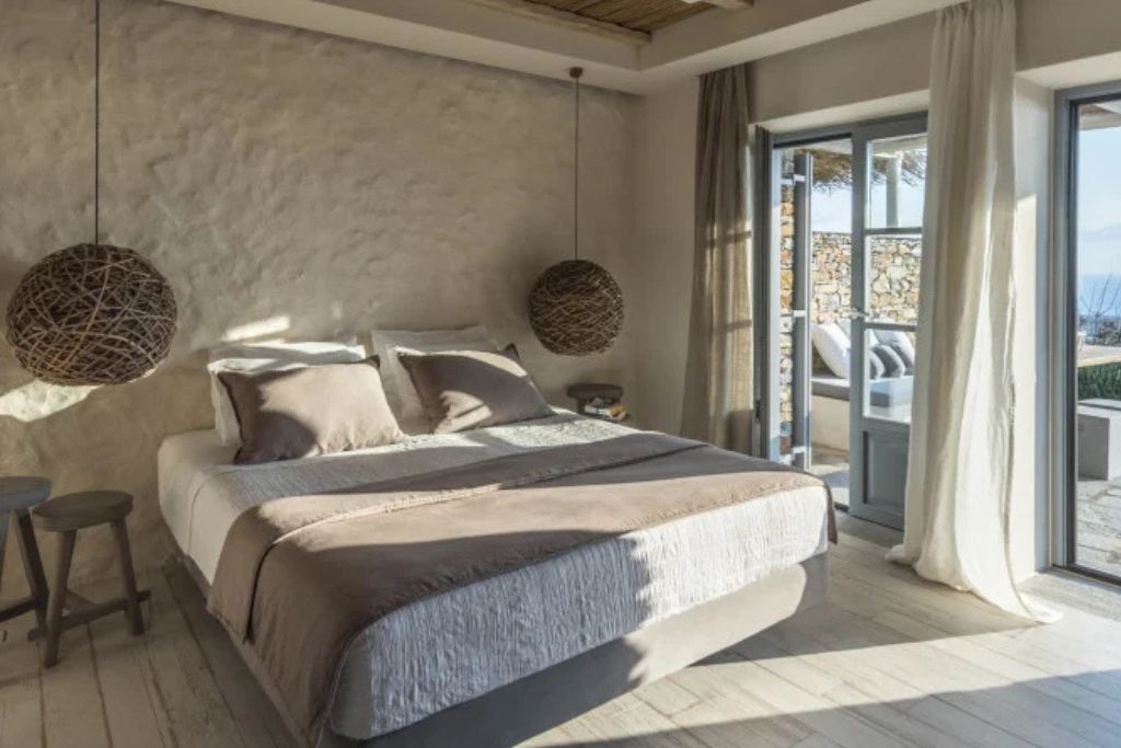 A view of the bed next to a patio with light coming in the window in the luxury suite in the Verina Astra hotel