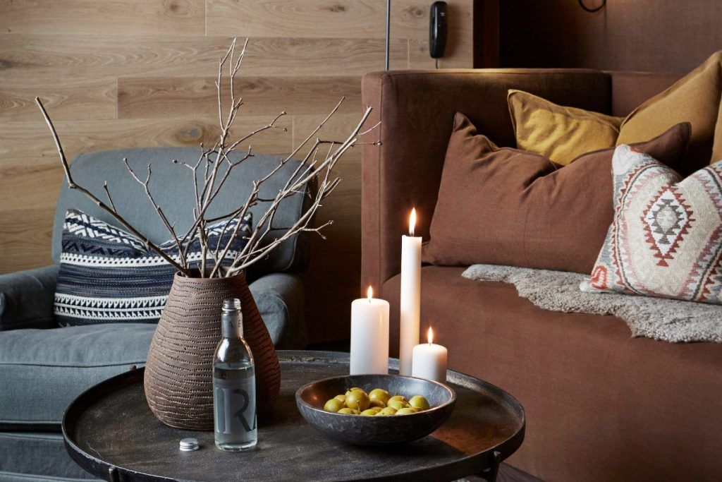 Candles on a table next to a plant in a living space at Storfjord Hotel.