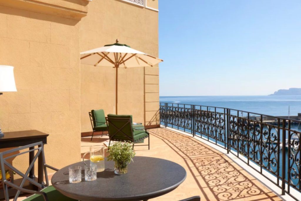 A balcony overlooking the sea with two glasses on a table at Villa Igiea.