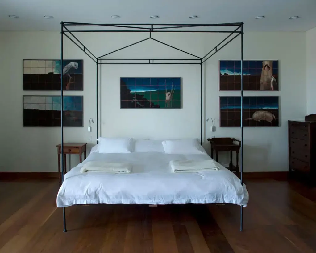 A view of the bed with art on the walls in one of the rooms of Estancia Vik.