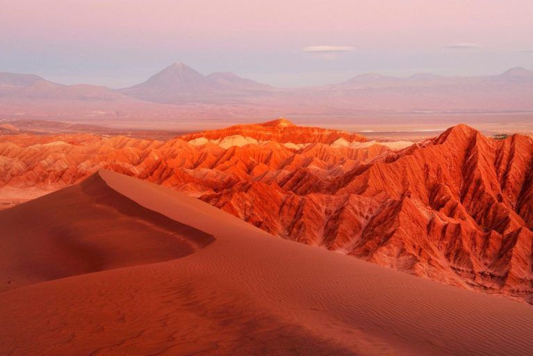 A sunset over the mountains and dunes in the Atacama Desert