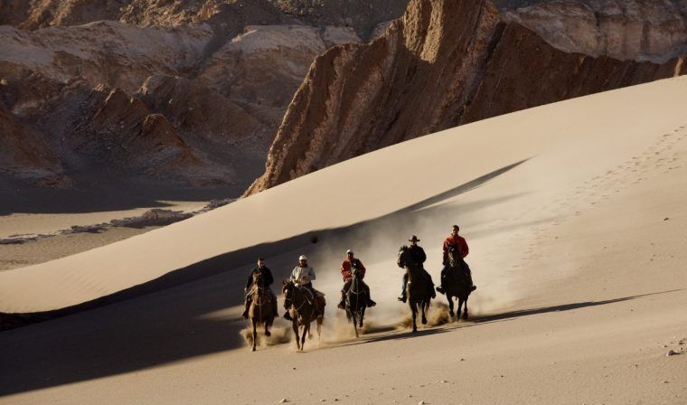 People riding horses in the Atacama Desert.