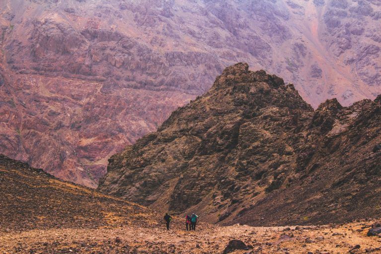 A view of hikers in the red mountains of Toubkal.