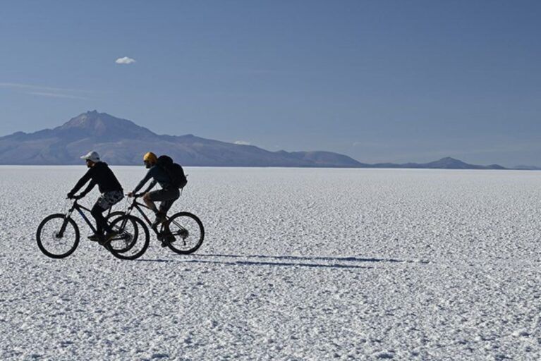 Two travelers embarking on a private biking excursion across the Bolivian Salt Flats during luxury tour