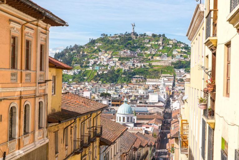 A view down a street in Quito Ecuador showing a statue on a hill in the background
