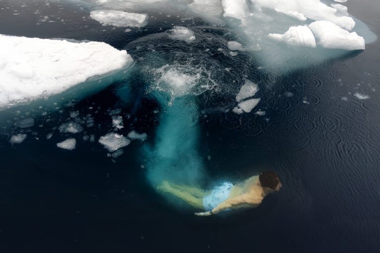 A person diving into the arctic waters of Svalbard